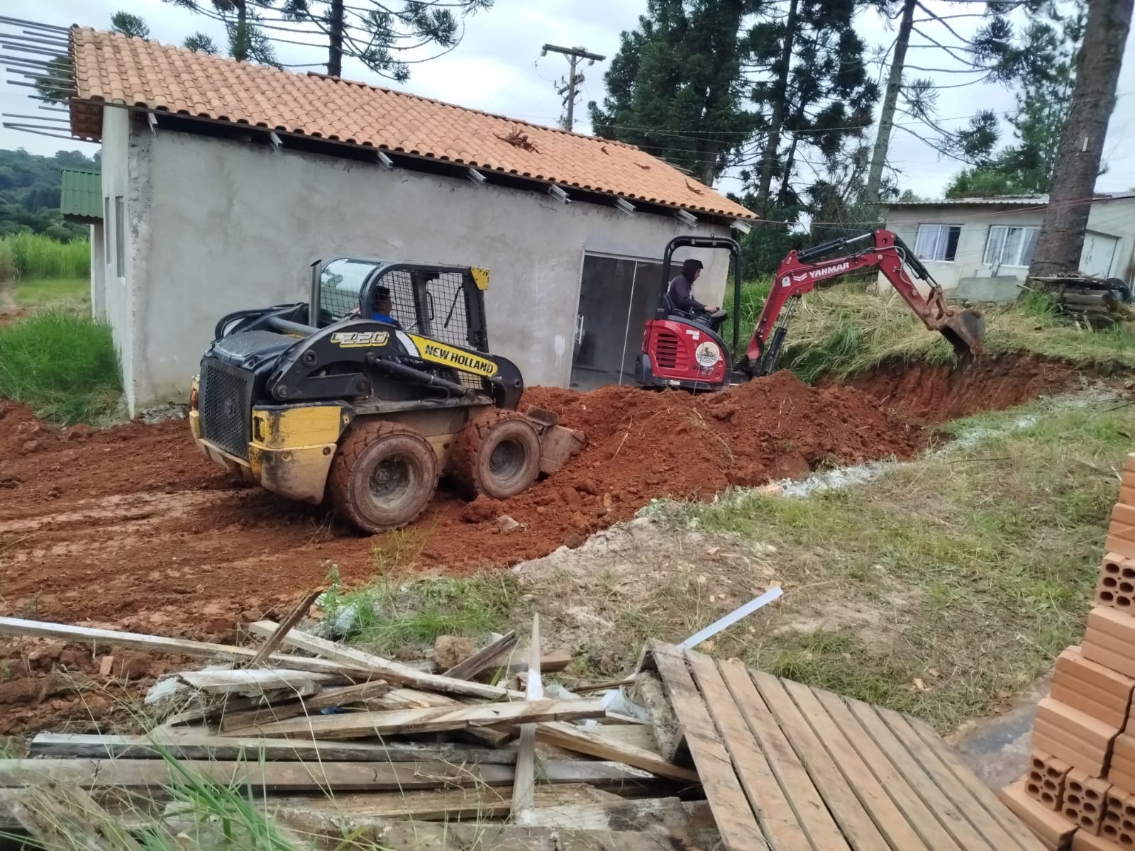 Mini carregadeira e mini escavadeira em movimentação de terra